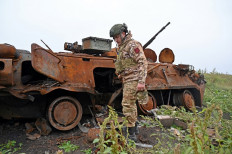 A serviceman of the National Guard of Ukraine inspect destroyed military equipment abandoned at a position formally held by the Russian army in the north of the Kharkiv region, on September 20, 2022. 
