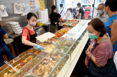 This photo taken on September 18, 2022 shows customers being served low-priced two-dish mealboxes at Kitty Chan's restaurant in Hong Kong.