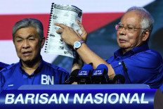 This picture taken on April 7, 2018 shows then Malaysian Prime Minister Najib Razak (right) pointing to the opposition manifesto before launching his coalition's own election manifesto ahead of the upcoming polls during a National Front coalition or Barisan Nasional rally, in Kuala Lumpur. 