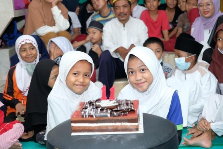 Bunga and Azzizah blow out the birthday cake candles.