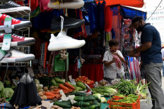 A man buys a vegetables from a street stall in Quiapo, Manila, on July 5, 2022.