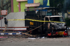 A policeman sets up a cordon next to a torched vehicle outside Kanjuruhan stadium in Malang, East Java on October 2, 2022. At least 127 people were killed when angry fans invaded a football pitch after a match in Malang, East Java  late on October 1, police said.
