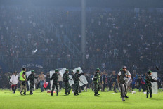 This picture taken on October 1, 2022 shows members of the Indonesian Army securing the pitch after a football match between Arema FC and Persebaya Surabaya at Kanjuruhan stadium in Malang, East Java. 