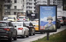 Cars roll past a billboard displaying Russian Airborn Specialist Kirill Ryzhonkov with a slogan reading 'Glory to the Heroes of Russia' in central Moscow on September 28, 2022. Russia announced the call up of some 300,000 reservists to bolster the war effort and cautioned that Moscow would use 