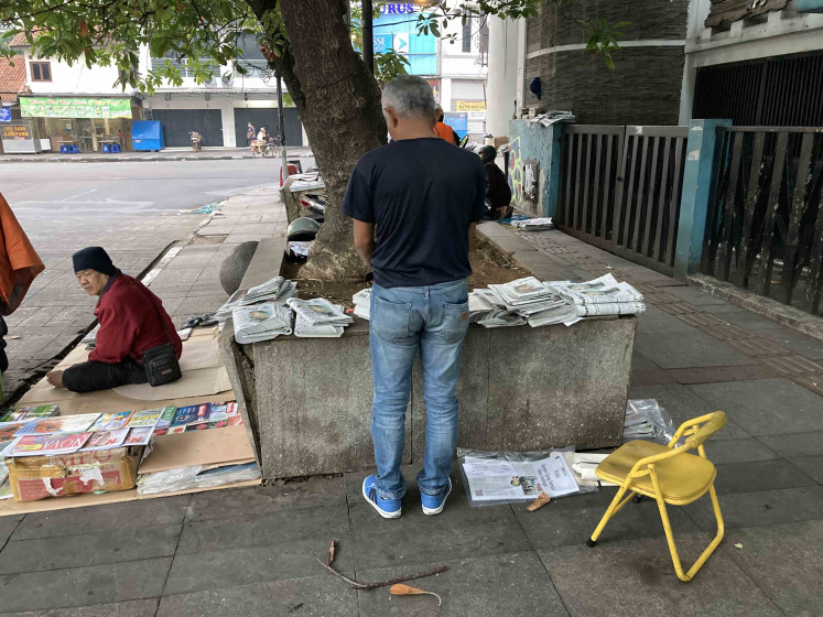 Point of no return: Dedy  goes through his newspaper stock not long after daybreak, matching his inventory with the hand-written note that he has kept while monitoring the circulation since 3:30 a.m. (JP/Anindito Ariwandono)