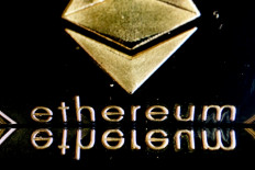 In this photo illustration created in Washington, DC, on September 15, 2022, the Ethereum logo on a physical imitation of an Ethereum cryptocurrency is reflected on a phone screen.
