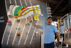 Didier Grande, tosses in the air one of the fan shemagh scarves, also known as ghutra or keffiyeh, that he designed with his business partner in the national colours of the 32 countries taking part in the World Cup tournament, inside their shop in the Qatari capital Doha, on September 27, 2022.