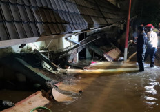 Firefighters and officials from the Jakarta Disaster Mitigation Agency (BPBD) comb along the perimeter of a collapsed wall separating a residential area and the state Pondok Labu Madrasah Tsanawiyah (MTSN) 19 Islamic junior high school in Cilandak, South Jakarta, on Oct. 6, 2022. Three schoolchildren have been pronounced dead after a wall collapsed on them due to the sheer force of floodwaters that inundated the area Thursday afternoon.