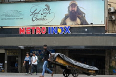 Pedestrians walk past a poster of the upcoming Bollywood film 'Laal Singh Chaddha' put up at the Metro theatre in Mumbai on August 8, 2022.