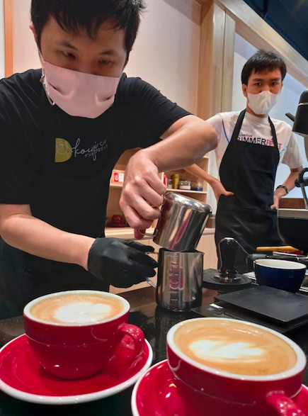 At a workplace: Kouji (wearing a black shirt) demonstrated to other workmen (baristas) in Kouji Genki Project how to do milk frothing for a latte. (Courtesy of Yumiko Hirano)