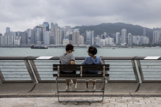 Two women sit on a bench over looking Victoria Harbour in Hong Kong, China, on Sept. 29, 2022.
