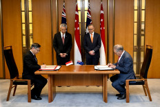 Singapore's Prime Minister Lee Hsien Loong (centre left) and Australian Prime Minister Anthony Albanese (centre right) observe the signing of the Singapore-Australia Green Economy Agreement between Minister for Trade of Singapore Gan Kim Yong (L) and Australian Minister for Trade Don Farrell (R) during a signing ceremony at Parliament House in Canberra on October 18, 2022. 
