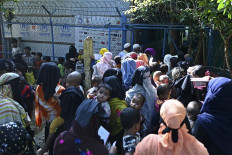 In this picture taken on September 29, 2022, Rohingya refugees gather outside a relief supplies distribution point at Kutupalong refugee camp in Ukhia.