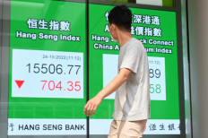 A pedestrian passes a sign showing the numbers for the Hang Seng Index in Hong Kong on Oct. 24, 2022. Hong Kong stocks plunged that day as investors were spooked by Chinese President's decision to hand key economic posts to loyalists who back his zero-COVID strategy.
