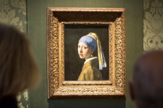 Attack on art: Visitors look at Johannes Vermeer's painting Girl with a Pearl Earring at the Mauritshuis museum in The Hague, on Thursday. Dutch police arrested three people after climate activists targeted the painting.