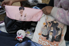 Jin fever: A fan of the South Korean band BTS on Wednesday shows a scarf with the portrait of Jin (left) while camping near River Plate's Monumental stadium to attend Coldplay's Friday concert in Buenos Aires. 