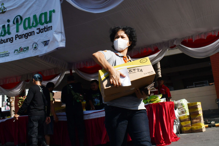 A resident carries a box of groceries during a subsidized market day at Sleko Market in Madiun, East Java, on Oct. 30, 2022. The East Java administration sold rice at Rp 52,000 (US$3.34) per kilogram, cooking oil at Rp 12,500 per liter and sugar at Rp 12,000 per kg amid global and domestic inflation pressures. (Antara/Siswowidodo)