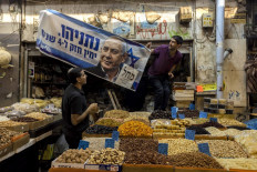 An electoral banner for Israel's Likud party, depicting its leader and former prime minister Benjamin Netanyahu, is hung above a nut and dried fruit stall at the Mahane Yehuda market in Jerusalem on October 31, 2022, one day ahead of the November general elections. 
