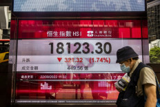 A man walks past an electronic sign showing numbers of the Hang Seng stock market index in Hong Kong, China, on Sept. 22, 2022, when Hong Kong shares were trading near a decade low.
