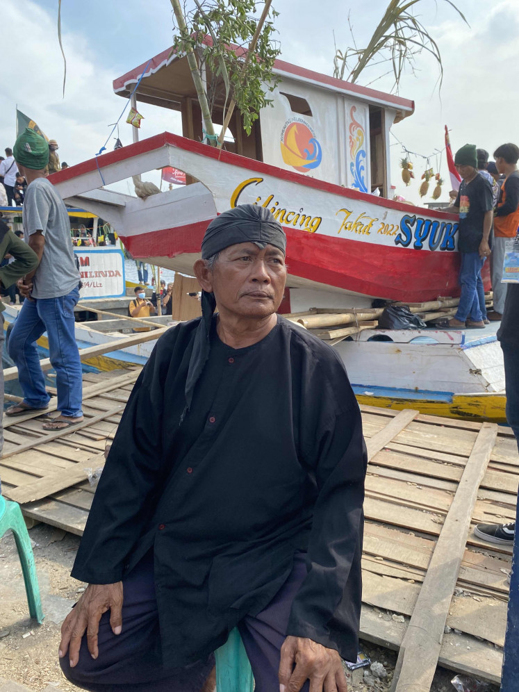 Village figure: Sarkim, 67, the 'juru kunci' (spiritual guide) of Kampung Nelayan Cilincing's 'pesta laut' in North Jakarta guards the boat of offerings and whispers prayers before the ritual begins on Oct. 22. (JP/Harriet Crisp)