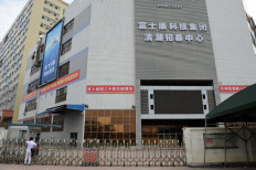 This file photo taken on February 22, 2013 shows a man waiting outside the gate of a Foxconn recruitment center in Shenzhen, south China's Guangdong province. Chinese authorities locked down the area surrounding the world's largest iPhone factory on November 2, 2022, after workers fled to avoid a coronavirus outbreak and the resulting restrictions. 
