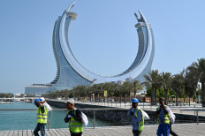 Workers walk along the marina near the Katara Towers in the Qatari coastal city of Lusail on October 23, 2022, ahead of the Qatar 2022 FIFA World Cup.