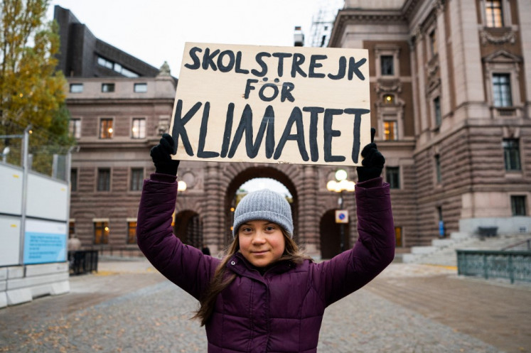 Swedish climate activist Greta Thunberg poses with a sign reading “School strike for Climate“ as she protests in front of the Swedish Parliament (Riksdagen) in Stockholm, on Nov. 19, 2021.