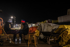 Photo taken October 27, 2022, shows Jakana Nelson (L) and Peter Kirya seen keeping guard on shops upon closure, following a presidential directive to impose curfew and Lockdown for 21 days in districts of Mubende and Kasanda to curb the spread of Ebola virus.