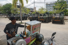 A hawker cooks up meatball soup beside police armored vehicles parked near the venue of the Group of 20 Summit in Nusa Dua, Bali on Nov. 12.