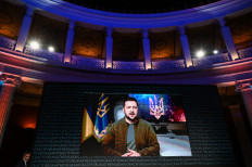Attendees watch a speech by Ukrainian President Volodymyr Zelensky displayed a on a screen during the Athens Democracy Forum, at the Zappeion Hall in Athens on Sept. 28, 2022.