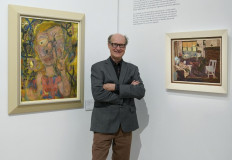 James Warhola, US artist and illustrator, stands next to his uncle Andy Warhol’s 'Nosepicker 1: Why Pick on Me' and 'Living Room' on display November 10, 2022 at Phillips Auction House in New York.