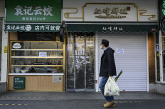 A man carrying a bag of vegetables walks past closed shops in Beijing’s Chaoyang district due to COVID-19 restrictions on Nov. 19, 2022.