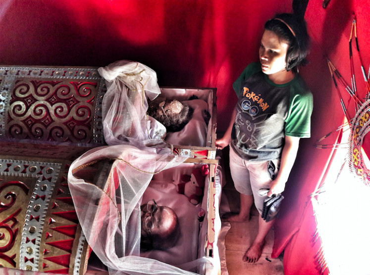 Masa Lalu yang Berlama-lama: Seorang penduduk Doraja mengunjungi kerabatnya yang telah meninggal.  Para pelayat di pemakaman Thana Toraja 
