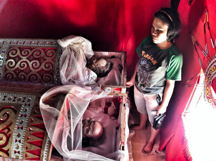 The lingering past: A Toraja resident visits her dead relatives. Eveleigh describes mourners at a Tana Toraja funeral as acting like “they are in a punk rock mosh-pit rather than a group of pallbearers as the barging, swaying gang of sweating, black-shirted youths tried to knock each other off their feet or wrench the bamboo poles away.” (Courtesy of Mark Eveleigh)