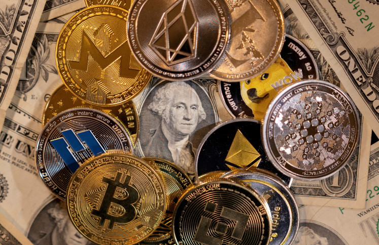 Representations of virtual cryptocurrencies are placed on US dollar banknotes in this illustration taken on Nov. 28, 2021.
