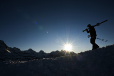 Ski season is coming: A skier holds his ski and walks at sunset along the Lauberhorn Peak in Wengen, Switzerland, on Jan. 14. Switzerland is counting on the trains to bring young European holiday makers during the forthcoming ski season, the national tourism agency said on Wednesday.