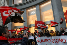 People hold flags from Spain's CGT labour union as they protest outside a Zara clothing store, an Inditex brand, for an increase in salaries amidst inflation hikes, in Madrid, Spain, November 24, 2022. 
