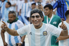 A supporter wearing a mask depicting football legend Diego Maradona poses for pictures before the Qatar 2022 World Cup Group C football match between Argentina and Saudi Arabia at the Lusail Stadium in Lusail, north of Doha on November 22, 2022.