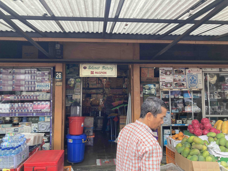 Coexisting: A man observing fruits at a stall in front of electrical supply shop Sinar Terang. Most of the shops adjacent to sinar terang are mixed-use, where the owners conduct business downstairs while keeping the second floor for living space. “They're less prone to the price hike,” Anton, the proprietor of Trikuto coffee shop, said. (JP/Anindito Ariwandono)