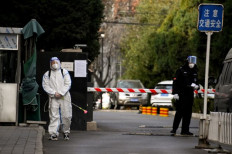 Protocols prolonged: A worker wearing personal protective equipment and a security official stand by the entrance to a residential area under a COVID-19 lockdown in Beijing on Nov. 29, 2022. 