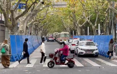 People walk past barricades and police presence in Shanghai on Nov. 28, 2022.