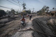 People salvage their belongings following a volcanic eruption by Mount Semeru at Kajar Kuning village in Lumajang on December 5, 2022. Indonesia's Mount Semeru erupted on December 4 spewing hot ash clouds a mile high and rivers of lava down its side while sparking the evacuation of nearly 2,000 people exactly one year after its last major eruption killed dozens.
