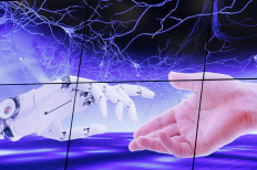 An illustration projected on a screen shows a robot hand and a human one moving towards each others during the “AI for Good“ Global Summit at the International Telecommunication Union (ITU) in Geneva, Switzerland, June 7, 2017. 