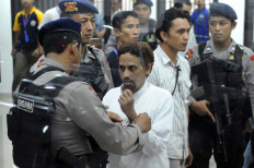 A police commando handcuffs convicted Islamic extremist Umar Patek (center) on June 21, 2012 after a Jakarta court sentenced Patek for 20 years in jail for acts of terror related to the 2002 Bali bombing that killed 202 people. 