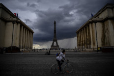 A man rides a bicycle past the Trocadero Esplanade as dark rain clouds loom over The Eiffel Tower in Paris on May 9, 2020, on the 54th day of a lockdown in France aimed at curbing the spread of COVID-19, caused by the novel coronavirus. 
