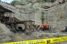 Surviving miners look on as rescue teams evacuate dead and injured victims of a coal mine explosion in Sawahlunto on December 9, 2022. 
