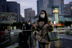 A woman wearing a face mask walks outside the Shanghai Railway Station in Shanghai, China, on Dec. 8, 2022.
