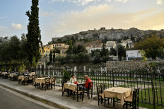 Tourists sit in an outdoor cafe-restaurant at the popular tourists Plaka area of Athens, before the sunset on December 8, 2022.