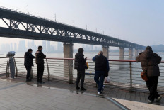 People stand on a promenade overlooking a river in Wuhan, Hubei province, on Dec. 10, 2022, a few days after the Chinese government started easing its COVID-19 curbs.