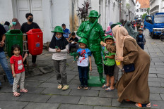 A woman gathers her children to pose for a photograph with a performer at the old town square in Jakarta on Dec. 18, 2022.